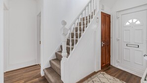 Eine Treppe mit weißen Geländern und einer Holztür am Fuß.