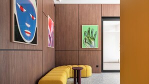 Un interior moderno con paneles de madera, un sofá amarillo y arte abstracto.