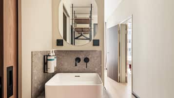 A bathroom with a rectangular sink, a mirror, and a towel rack.