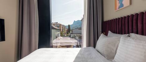 Camera d'albergo con un letto grande, vista sulla città e una moderna testiera.