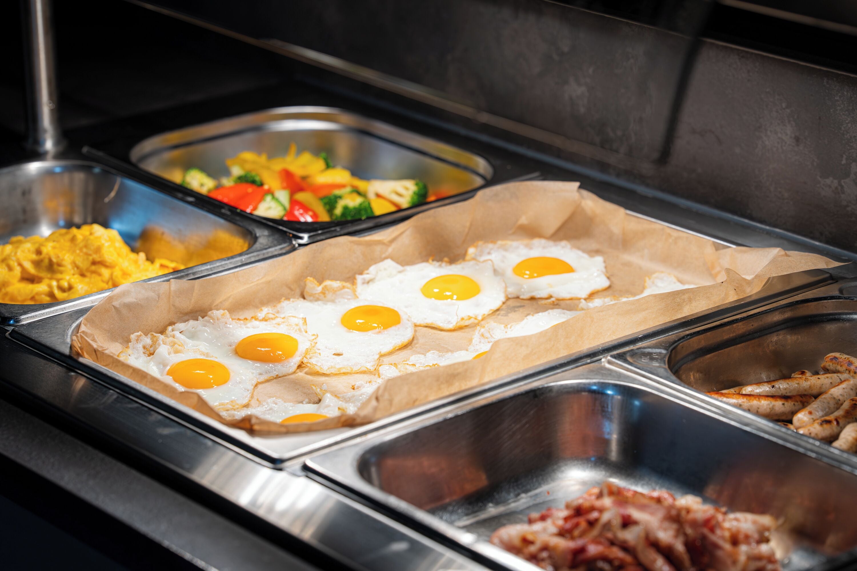 A buffet with various food options including eggs, vegetables, and meats.