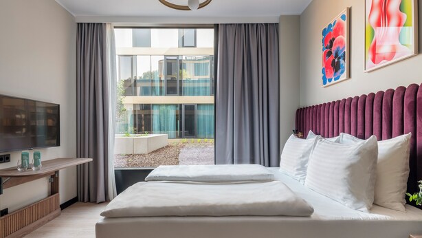 Habitación de hotel moderna con una cama grande, televisión de pantalla plana y vistas al exterior.