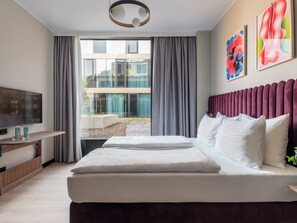 Habitación de hotel moderna con una cama grande, televisión de pantalla plana y vistas al exterior.