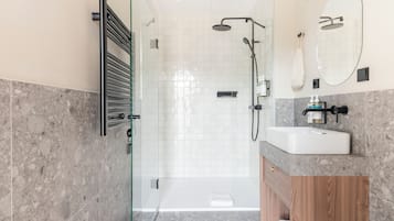 Un baño moderno con cabina de ducha de vidrio, tocador de madera y un espejo grande.