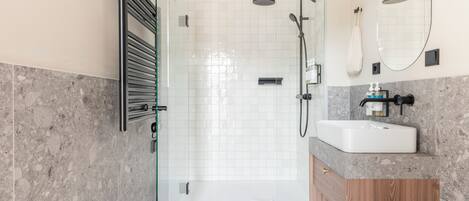 A modern bathroom with a glass shower enclosure, a wooden vanity, and a large mirror.