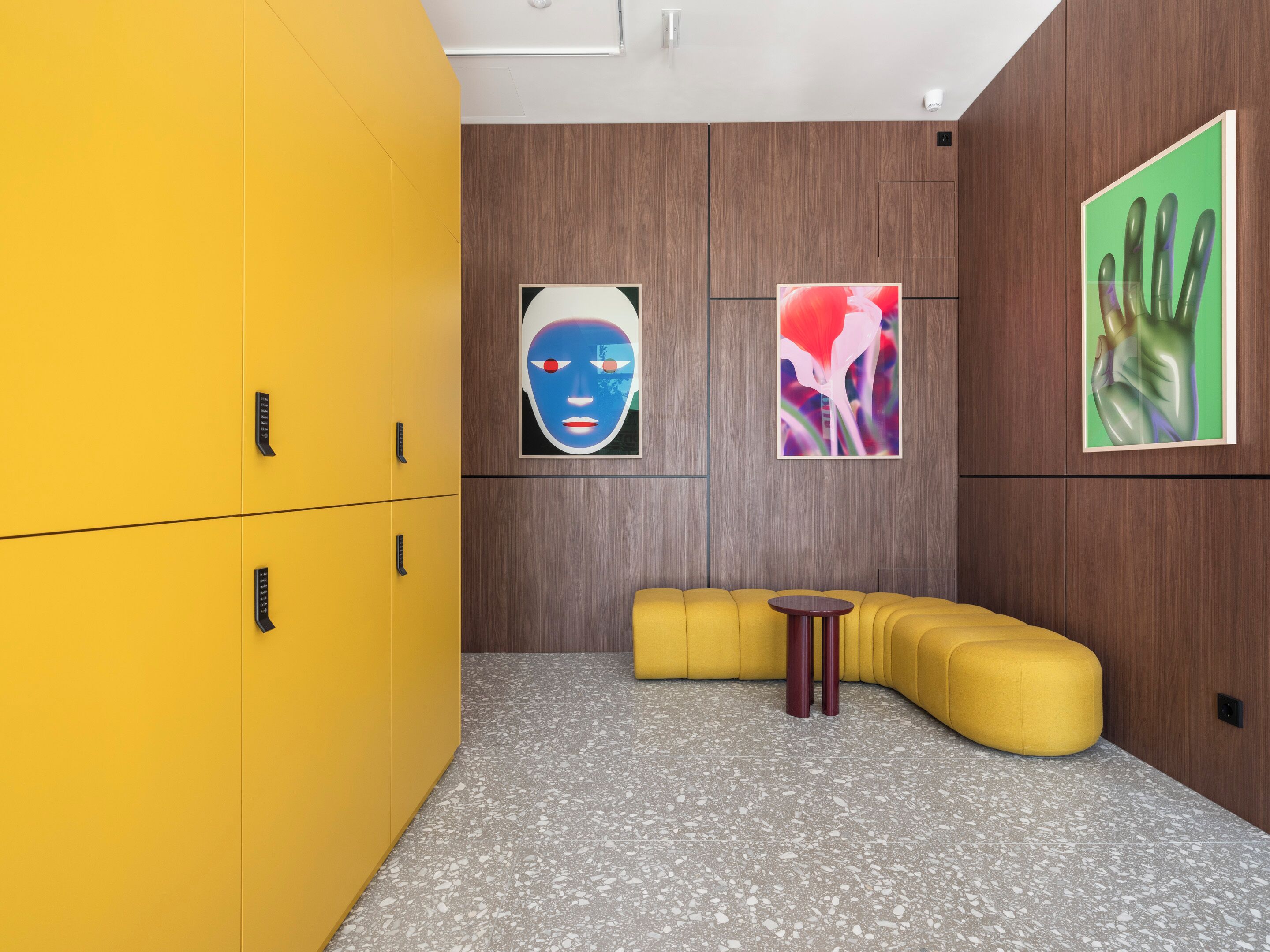 A modern room with a yellow sofa, a small round table, and wooden panel walls.