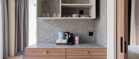 A modern kitchen with a granite countertop, a built-in shelf above the sink, and a wooden cabinet below.