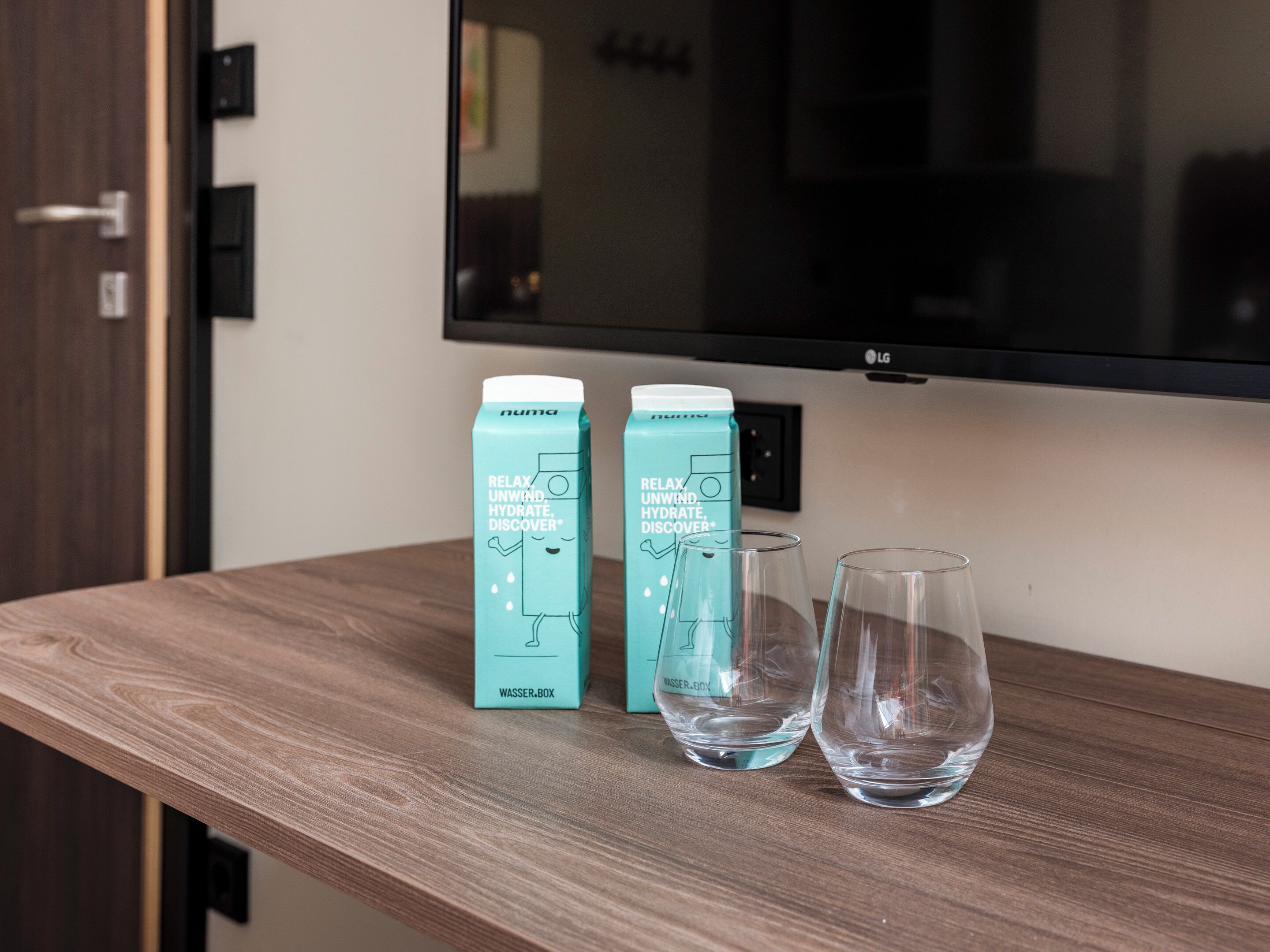A wooden table with two water bottles and two glasses.