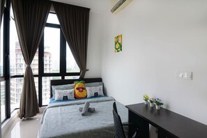 Une chambre à coucher comprenant un lit, un bureau, une chaise, une fenêtre avec des rideaux et un climatiseur fixé au mur.