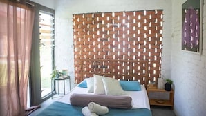 A bedroom with a bed, pillows, a bedside table, a window with curtains, and a brick-patterned wall. - Langkawi Rouhi Retreats at Langkawi (Langkawi)