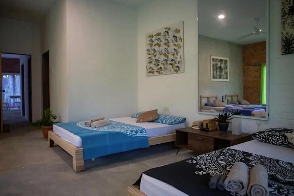 Un dormitorio con dos camas, cabecero de madera, una mesita de noche, un espejo y una obra de arte colgada en la pared.