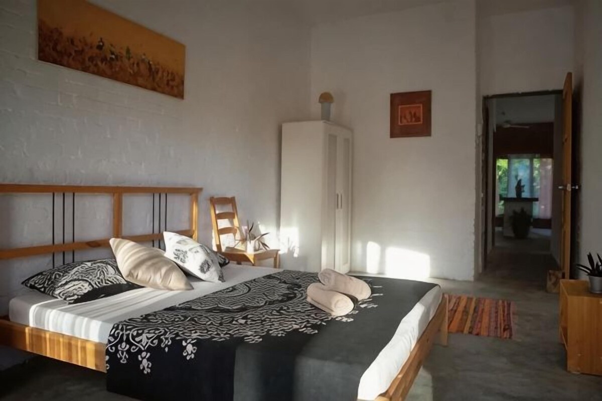 A bedroom with a bed, a wardrobe, and a door leading to another room.