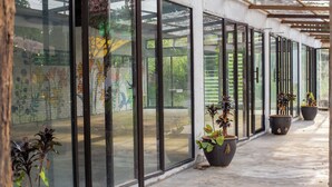 A covered outdoor area with large glass windows and potted plants. - Langkawi Rouhi Retreats at Langkawi (Langkawi)