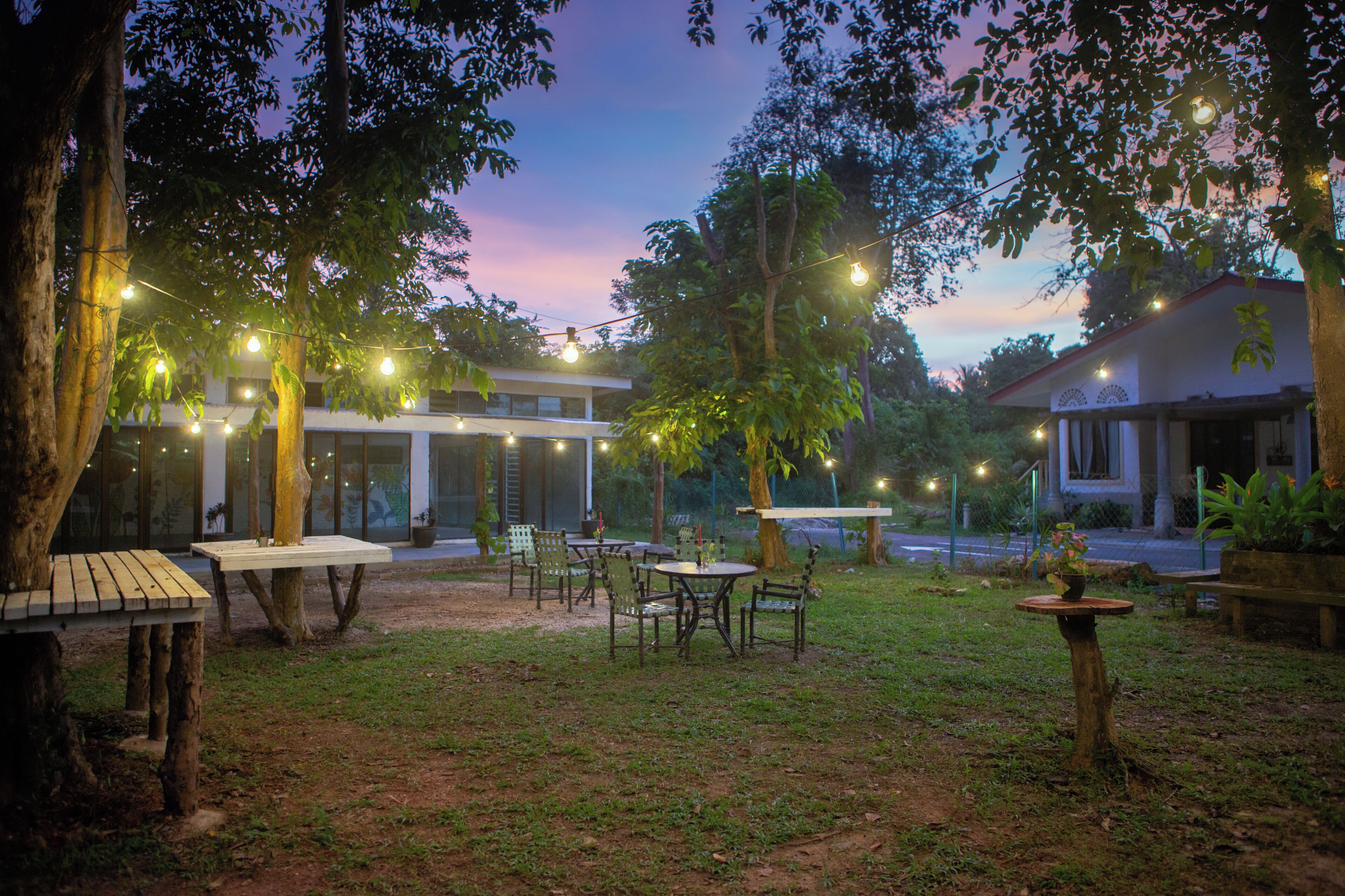 An outdoor patio area with tables and chairs, string lights, and a building in the background.