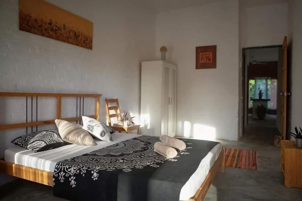 Quarto com cama, guarda-roupa e porta para outro cômodo.
