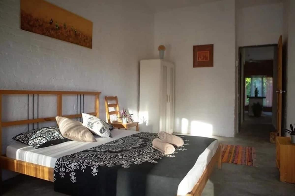 Um quarto com uma cama, um guarda-roupa, uma cadeira e um quadro na parede.