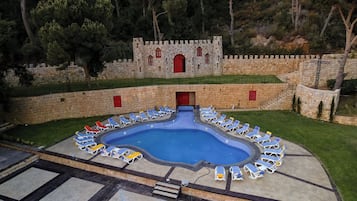 Una piscina al aire libre, sombrillas, sillones reclinables de piscina