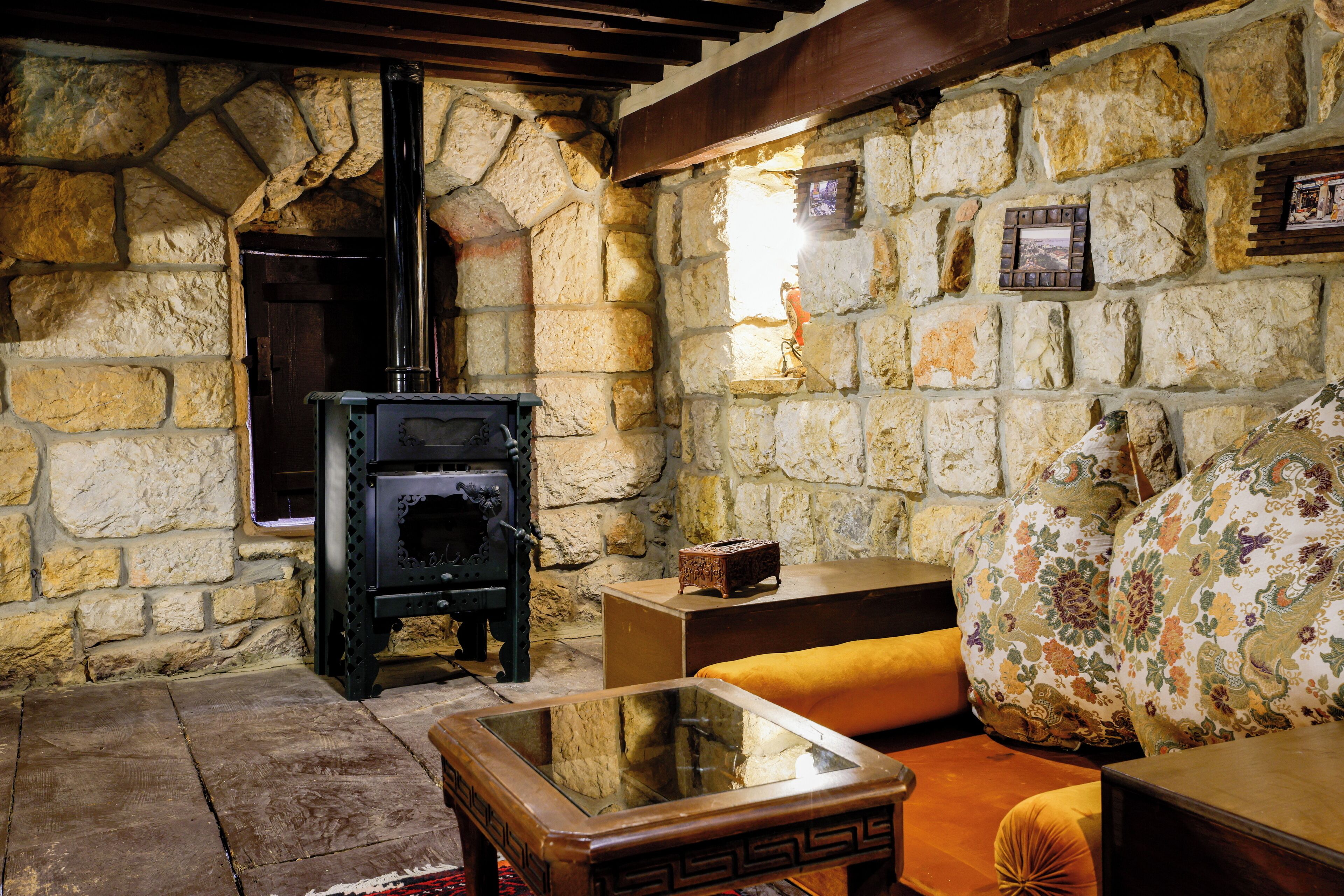 A stone-walled room with a fireplace, a sofa, and a glass-top coffee table.