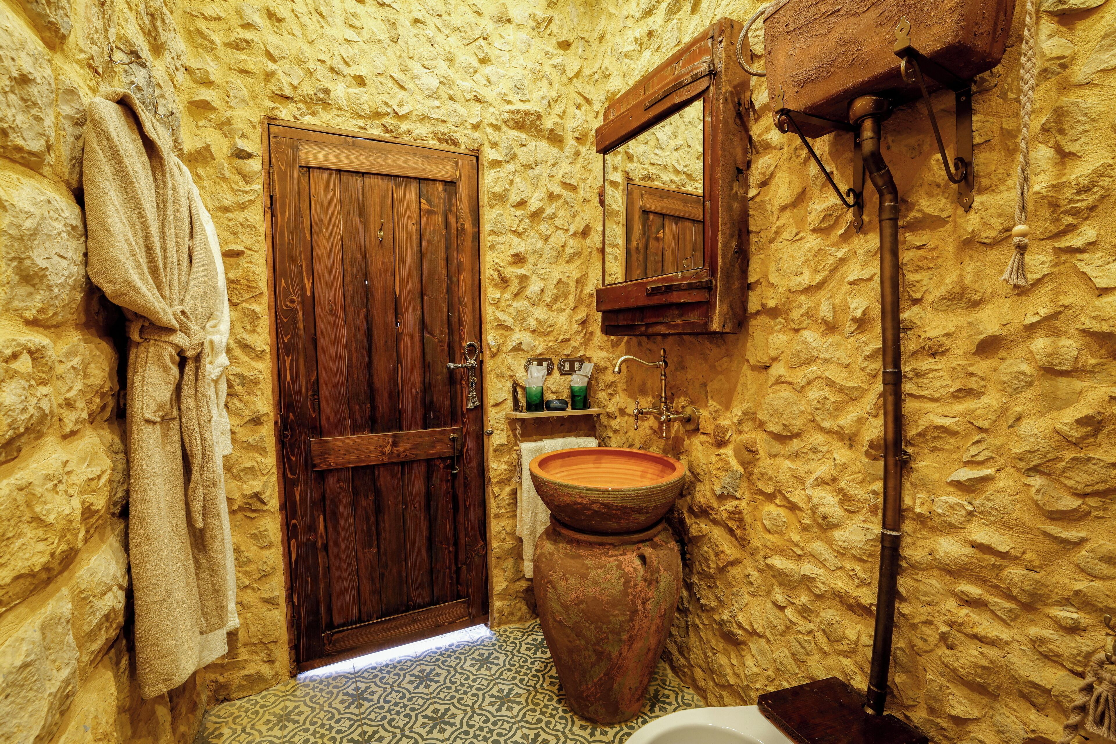 Un baño rústico con puerta de madera, un lavabo de cerámica grande y una toalla colgando.