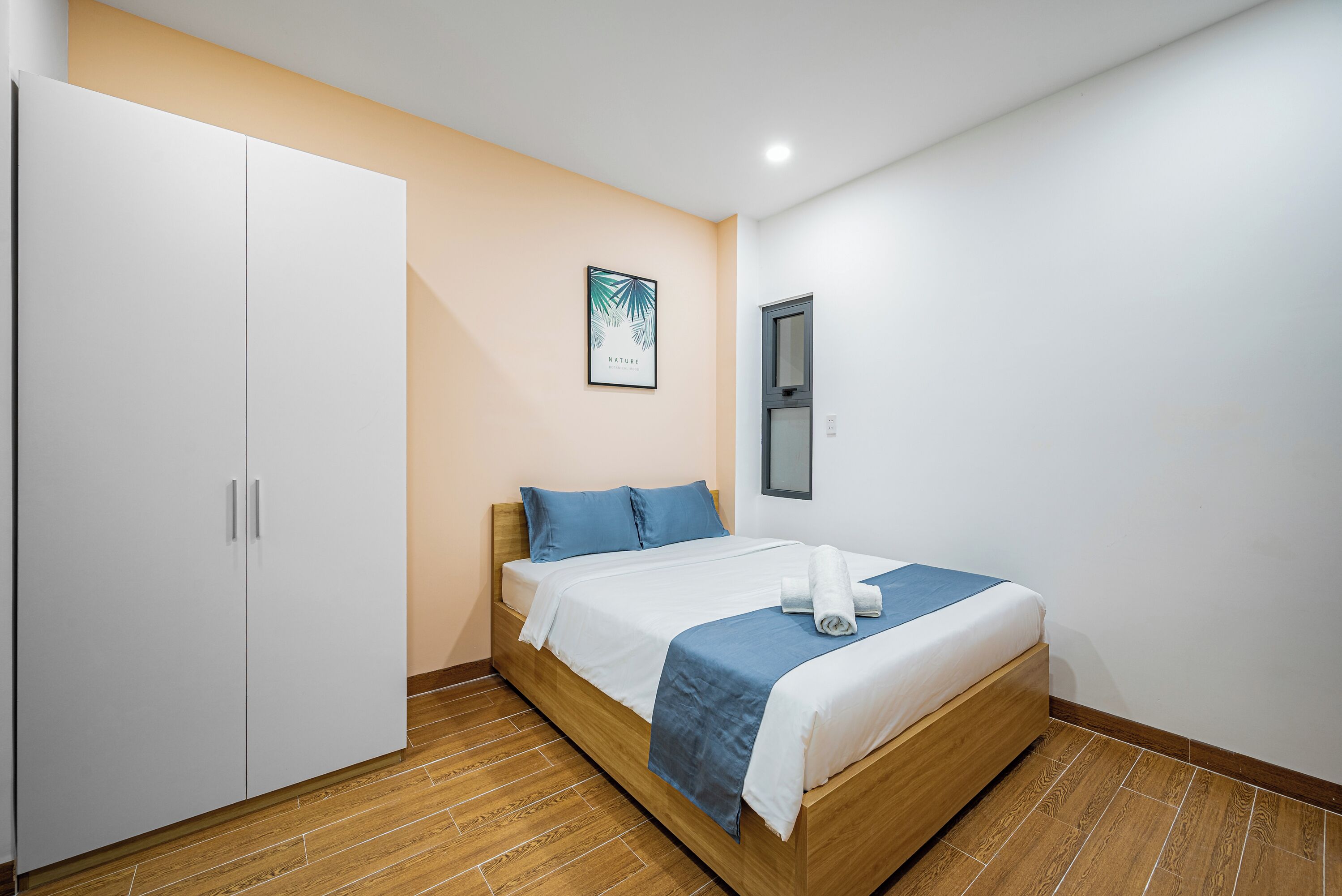 A bedroom with a bed, a wardrobe, and a framed picture on the wall.