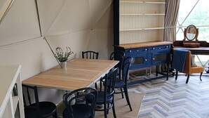 Uma tenda com mesa e cadeiras de madeira, um armário azul e um chão com padrão herringbone.