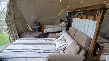 A tented accommodation with two beds, a small table, and a hanging rack.