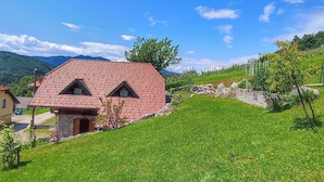 A house with a red-tiled roof, a stone foundation, and a small front porch. - Vineyard cottage Kralj (Dolenjske Toplice)