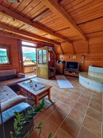Interior acogedor de una cabaña de madera con sofá, mesa de centro, televisor y chimenea.