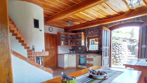 A rustic kitchen with wooden beams, a stone wall, and a view of the outdoors. - Vineyard cottage Kralj (Dolenjske Toplice)