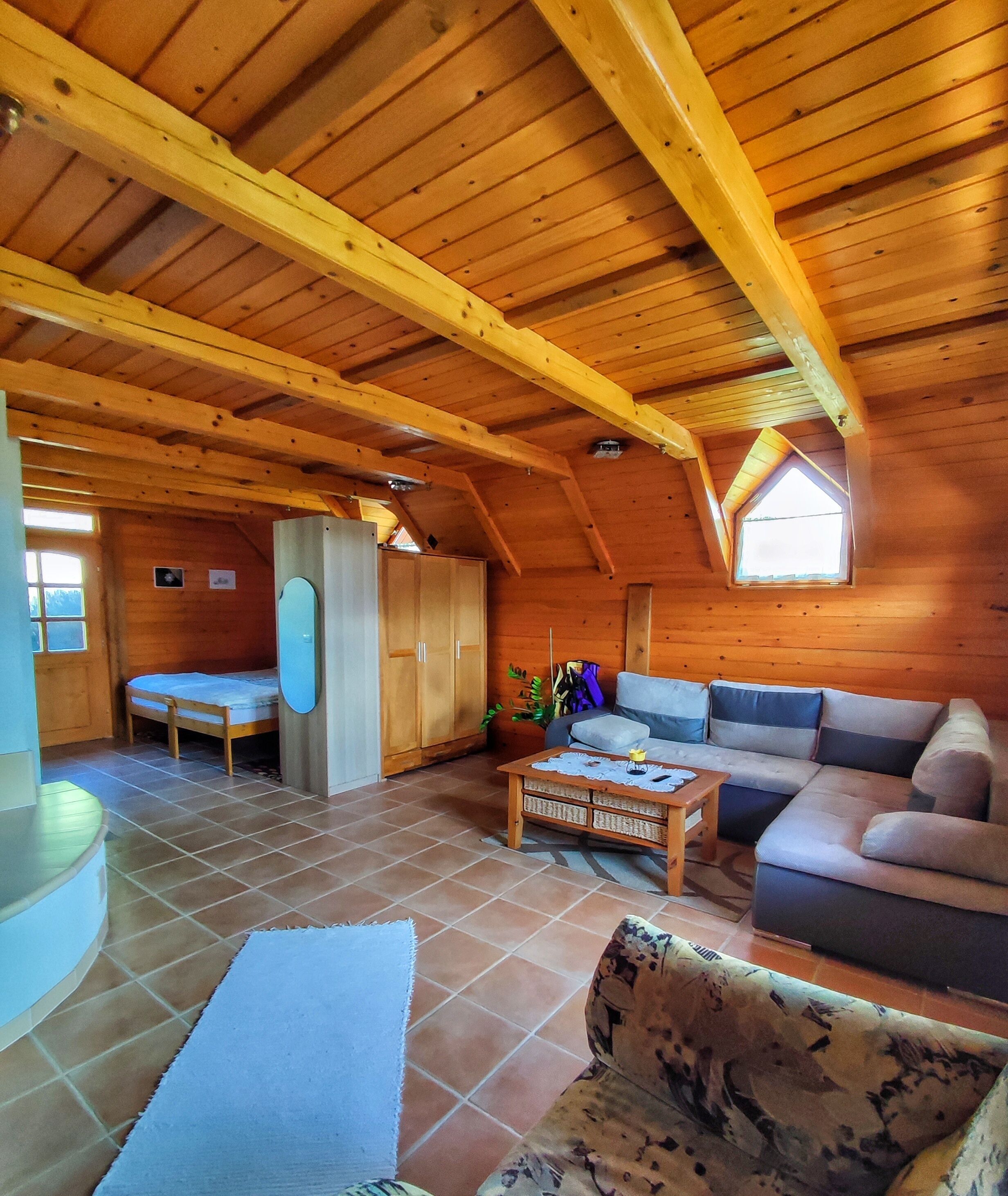 Ein gemütliches Holzhaus-Interieur mit Schlafkoje, einer Couch, einem kleinen Tisch und einem Fenster.