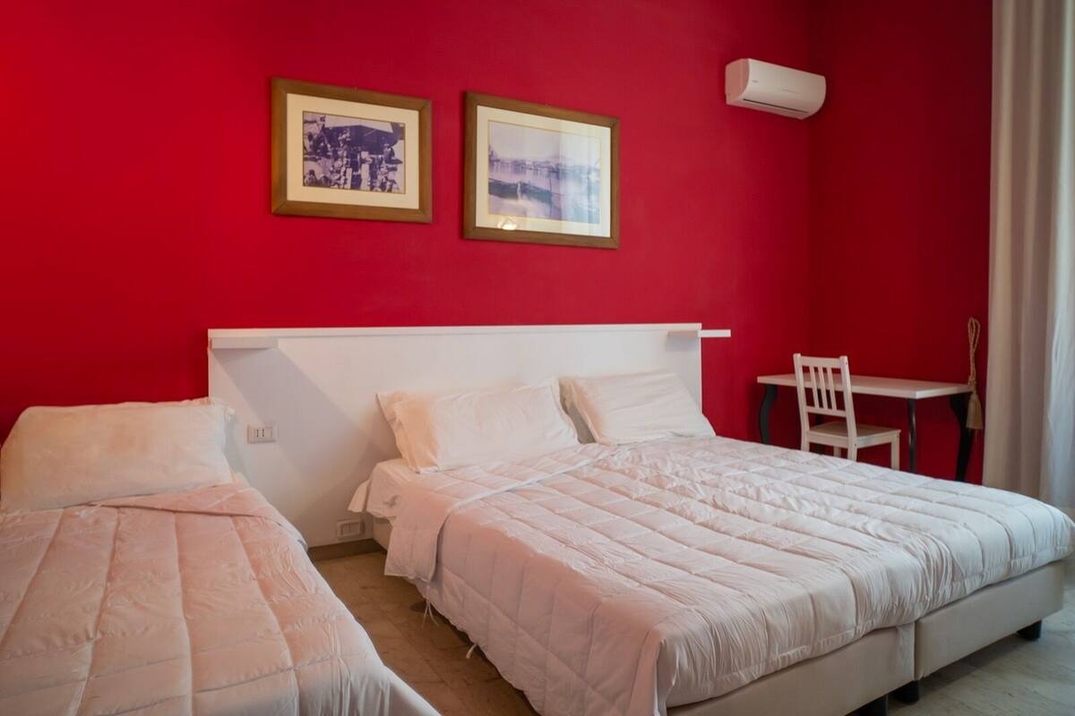 A hotel room with two beds, a small table, and two framed pictures on the wall.