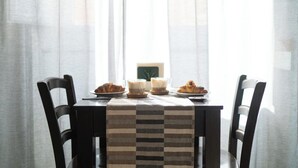 Een eettafel met een geruit tafelkleed, twee kaarsen en een lijst met een afbeelding.