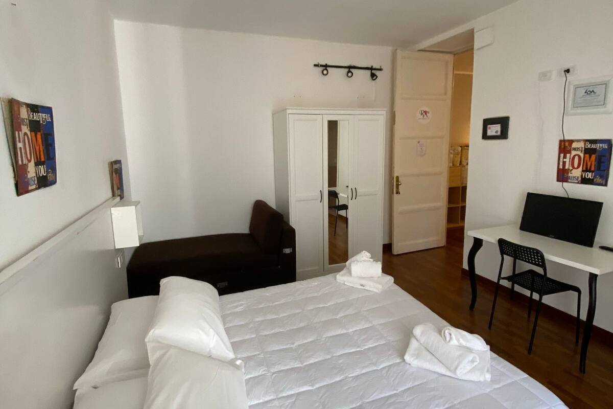 A neatly arranged hotel room with a large bed, a desk, and a chair.