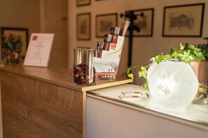 Uma mesa de recepção com um vaso de vidro, uma planta em vaso e um suporte para revistas.