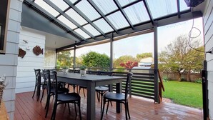 An outdoor patio with a covered dining area, a wooden deck, and a view of the backyard.