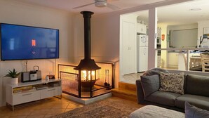 A living room with a TV, a fireplace, a sofa, and a kitchen in the background.