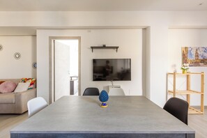Ein modernes Wohnzimmer mit einem grauen Sofa, einem Couchtisch und einem an der Wand montierten Fernseher.