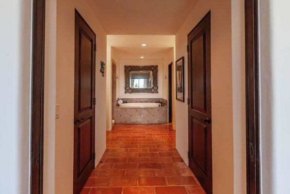 A hallway leading to a bathroom with a tiled floor, a sink, and a mirror. - Beautiful Residence at Hacienda Beach Club! (Cabo San Lucas)