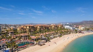 Un complejo turístico frente al mar con varias edificaciones, una playa y una zona de piscina.