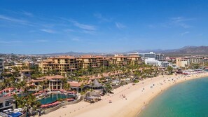 A coastal resort with multiple buildings, a beach, and a pool area.