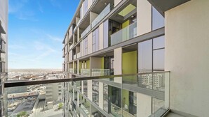 Ein Hochhaus mit zahlreichen Balkonen, großen Fenstern und freiem Blick auf die umliegende Stadtlandschaft.