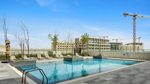 Ein Pool mit Liegestühlen, ein Baugebäude und ein Kran im Hintergrund.