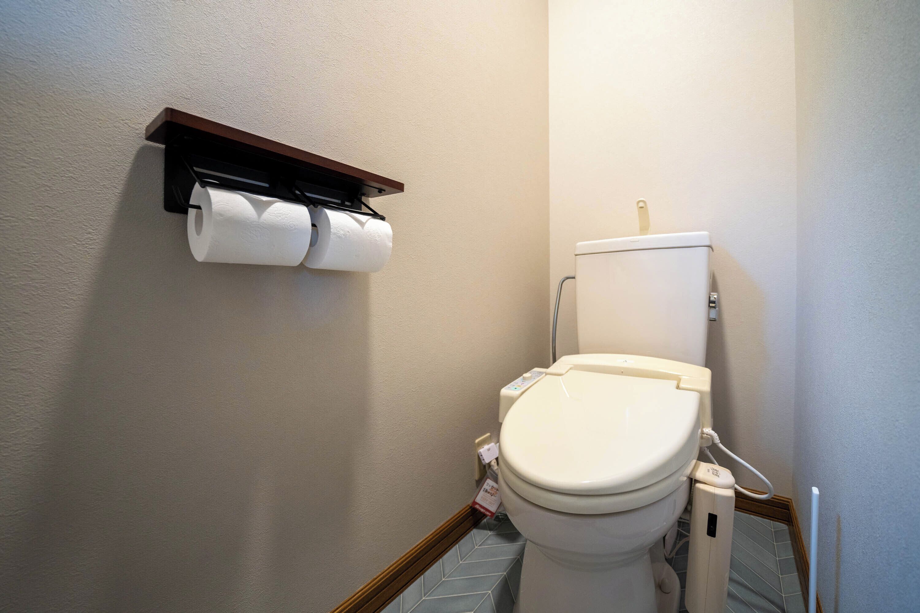 Un baño con inodoro, dispensador de toallas de papel y rollo de papel higiénico.