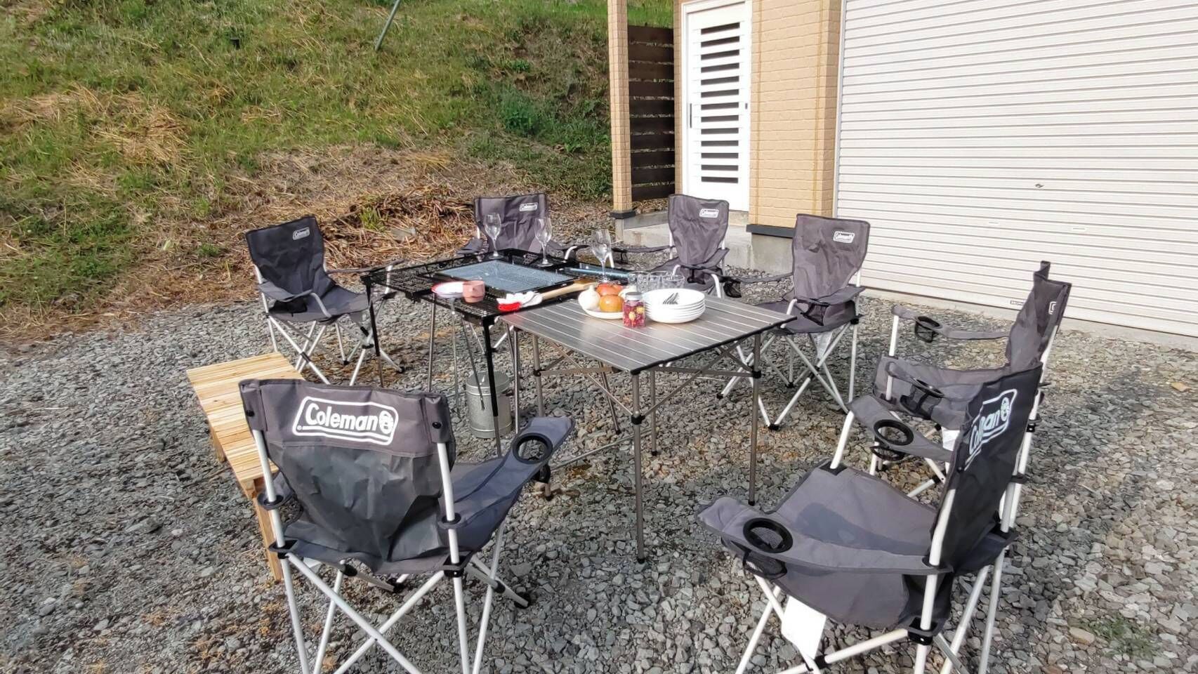 Mesa metálica con seis sillas de camping Coleman para comer al aire libre.