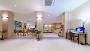 A modern hotel lobby with a reception desk, seating area, and a computer station. - Browndot Samcheonpo (Sacheon)
