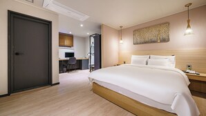 A modern hotel room with a large bed, a desk with a chair, and a small table with a lamp. - Browndot Samcheonpo (Sacheon)