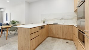 Une cuisine moderne avec des meubles en bois, un plan de travail en marbre et des appareils électroménagers en acier inoxydable.