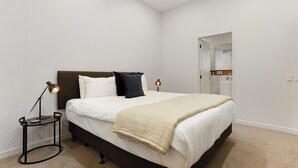 Une chambre à coucher avec un lit, des lampes de chevet, une table de chevet et un placard.