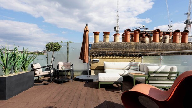 A rooftop terrace with outdoor furniture, potted plants, and terracotta pots. - Kensington Rooftops, by Veeve (London)