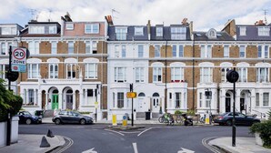 A street with terraced houses, a 20 mph speed limit sign, and a directional sign. - Kensington Rooftops, by Veeve (London)